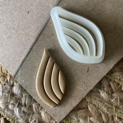 Cortador de biscoitos em forma de folha e biscoito correspondentes sobre várias superfícies