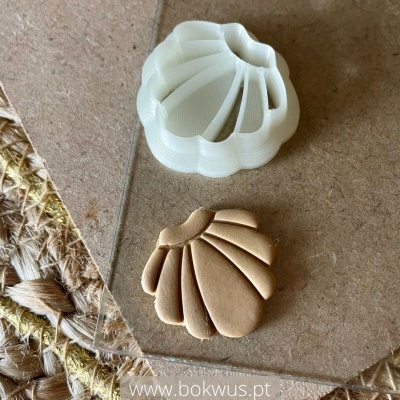 Moldes para corte em forma de concha, branco e castanho, sobre superfície de madeira