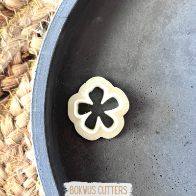 Cortador de massa em forma de flor branca dentro de recipiente cinzento