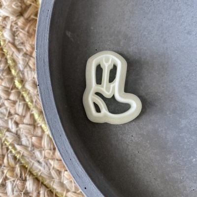 Crochet de plástico creme em forma de bota dentro de prato cinza em superfície de palha tecida