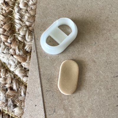 Objectos ovais branco e bege sobre cartão castanho e superfície trançada