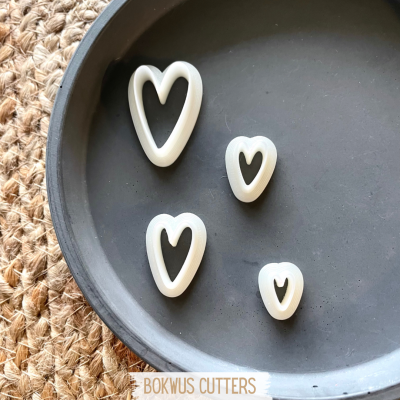 conjunto de quatro cortadores de biscoitos em forma de coração branco em bandeja preta