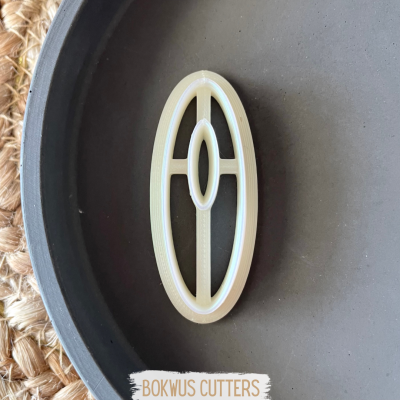 Cortante branco em formato oval com design geométrico sobre prato preto