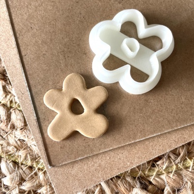 Cortador de biscoitos branco em forma de flor e massa de biscoito moldada em bege