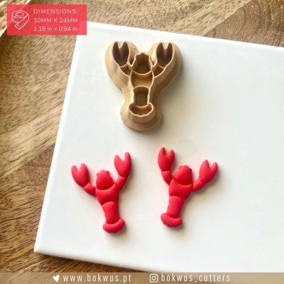 Cortantes de lagosta em bege e vermelho sobre placa branca e madeira com etiqueta de dimensões