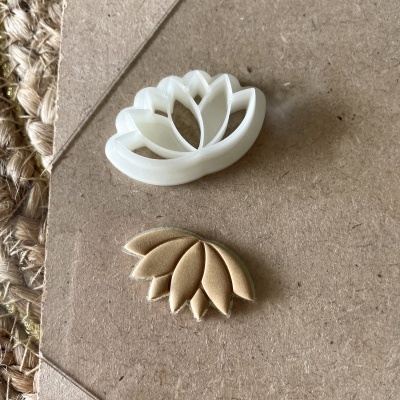 Dois cortadores de flores, um branco de plástico e um dourado de metal, sobre papel kraft