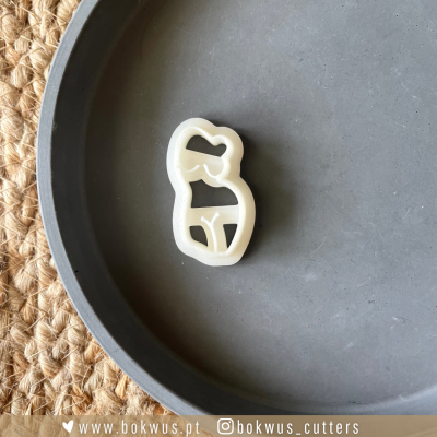 Cortador de bolachas branco em forma de mulher com biquíni numa placa cinza