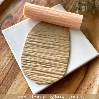 tábua branca com massa e rolo de massa creme clara sobre mesa de madeira