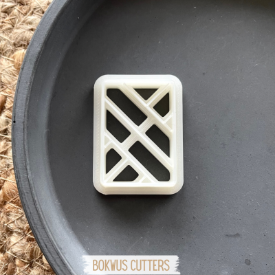 Cortador de bolachas branco com padrão geométrico recortado numa superfície preta