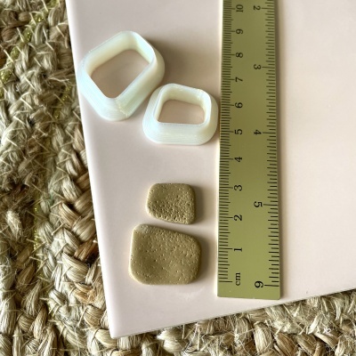 Anéis plásticos brancos e peças bege texturadas sobre superfície clara com régua amarela