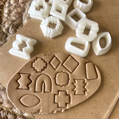 Moldes de corte plásticos brancos sobre cartão e massa castanha com formas recortadas