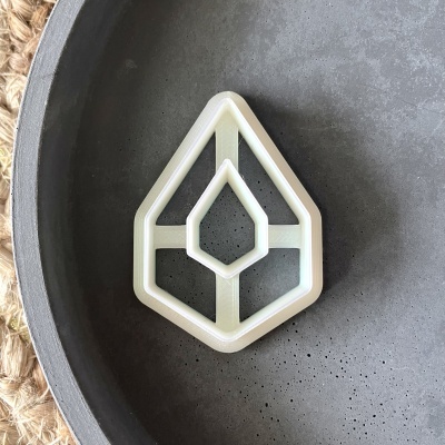 Cortador de biscoitos geométrico branco sobre prato cinza