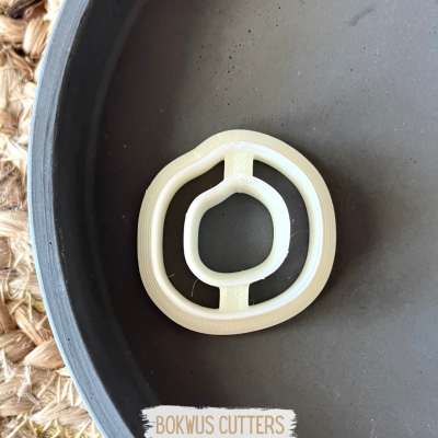 Cortador de massa oval branco num prato cinza escuro