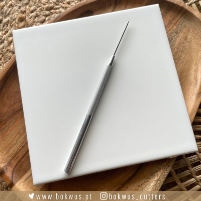 Ferramenta metálica de pontas finas sobre placa branca em bandeja de madeira