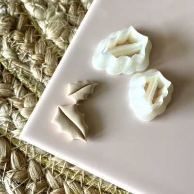 Cortadores de massa em forma de folhas e peças de massa sobre superfície rosa clara e esteira de fibra natural