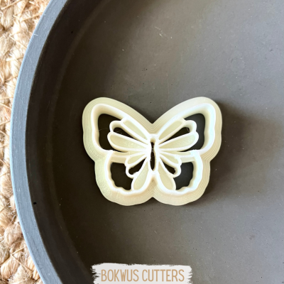 Cortante para bolachas em forma de borboleta branco sobre prato preto