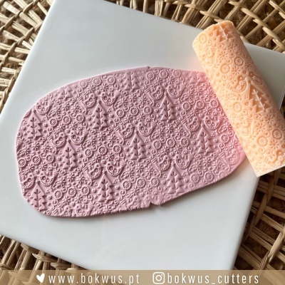 Rolo de textura em silicone laranja e pasta rosa decorada sobre prato branco