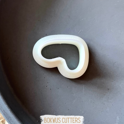 Cortador de biscoitos branco em forma de coração sobre superfície escura