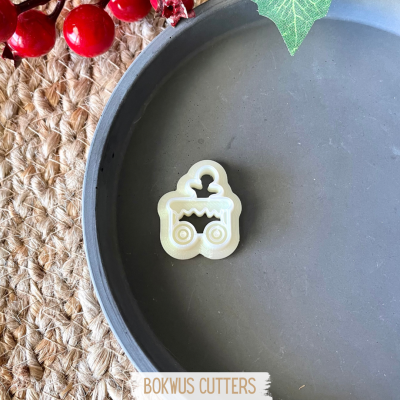 Selecionador de massa em forma de carrinho de bebé branco sobre travessa cinza e juta com bagas vermelhas