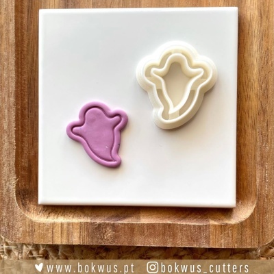 Cortante para bolachas e massa cor-de-rosa em placa cerâmica sobre tábua de madeira