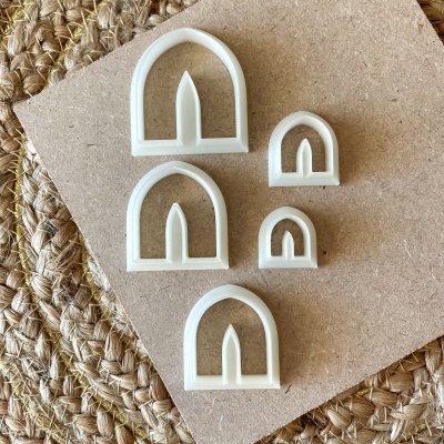 Conjunto de cortadores de massa brancos em forma de arco com ponta interna sobre madeira e tecido trançado