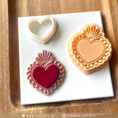 Moldes para cortar doces em formato de coração com texturas detalhadas numa base branca e tabuleiro de madeira