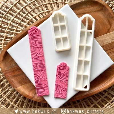 Relógios de corte para pastelaria em plástico branco e rosa sobre base de mármore e tabuleiro de madeira