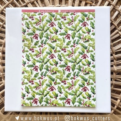 Papel decorativo com padrão festivo de folhas e bagas, sobre base branca e fundo de madeira entrelaçada