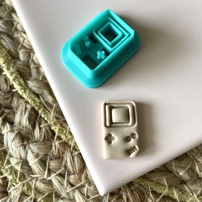 Molde azul de consola retro e peça branca feita com molde sobre superfície branca e tapete de fibra