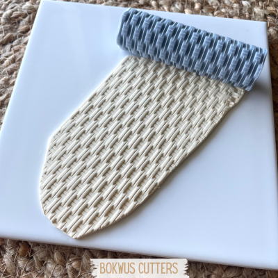 Rolo texturizado cinza com padrão em base branca e bege sobre tecido castanho