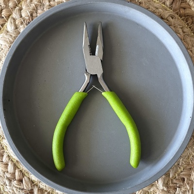 Alicate de ponta fina com cabos verdes num prato cinza