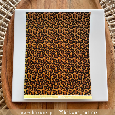 Papel decorativo com padrão de pele de leopardo sobre prato branco e tábua de madeira.