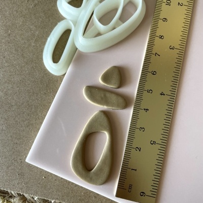 Formas de cortar e moldear em plástico branco e massa bege com régua amarela ao lado