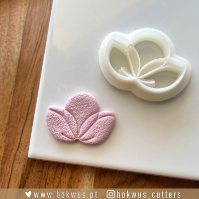 Cortante branco de flor com impressão rosa texturizada numa superfície branca e fundo de madeira