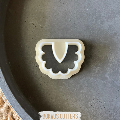 Cortador de biscoitos branco com bordas onduladas e forma triangular interior