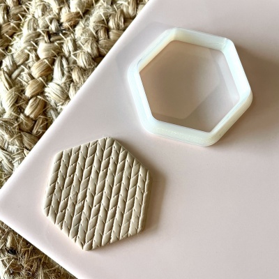 Cortador hexagonal branco e peça de argila bege com padrão trançado