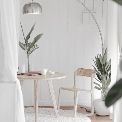 sala minimalista com mesa, cadeira, plantas e candeeiro