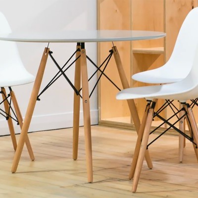 Mesa redonda branca com três cadeiras brancas com pernas de madeira clara