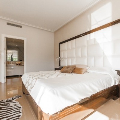 Quarto moderno com cama e cabeceira branca acolchoada e móveis de madeira