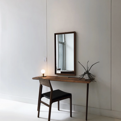 Mesa de madeira escura com cadeira e espelho retangular em ambiente minimalista