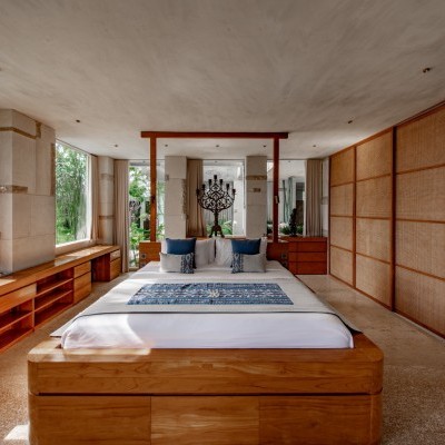 Quarto moderno com cama de madeira, almofadas azuis e vista para jardim