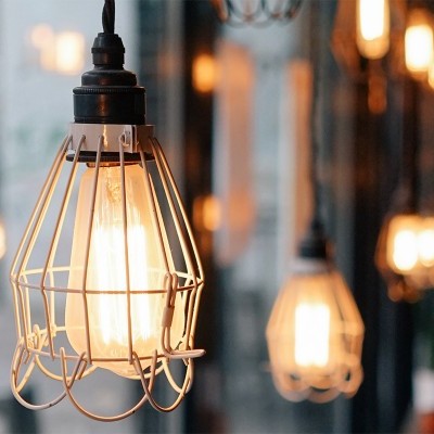 Candeeiro de teto metálico com lâmpada incandescente acesa num ambiente interior