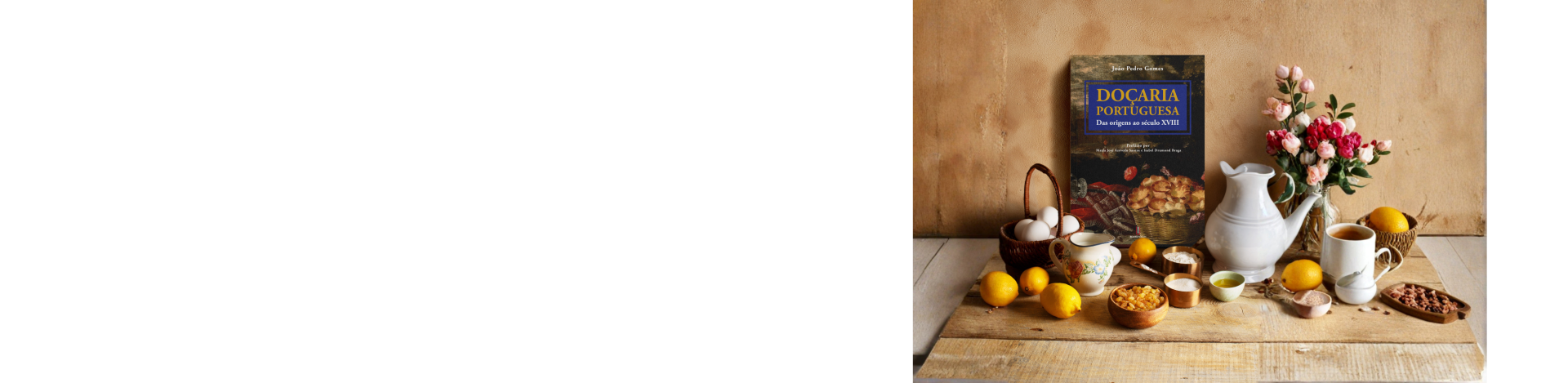 Livro DOÇARIA PORTUGUESA com ingredientes e jarra numa mesa de madeira