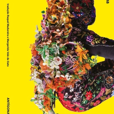 Capa de livro amarela com figura humana decorada com padrões florais coloridos e texto preto
