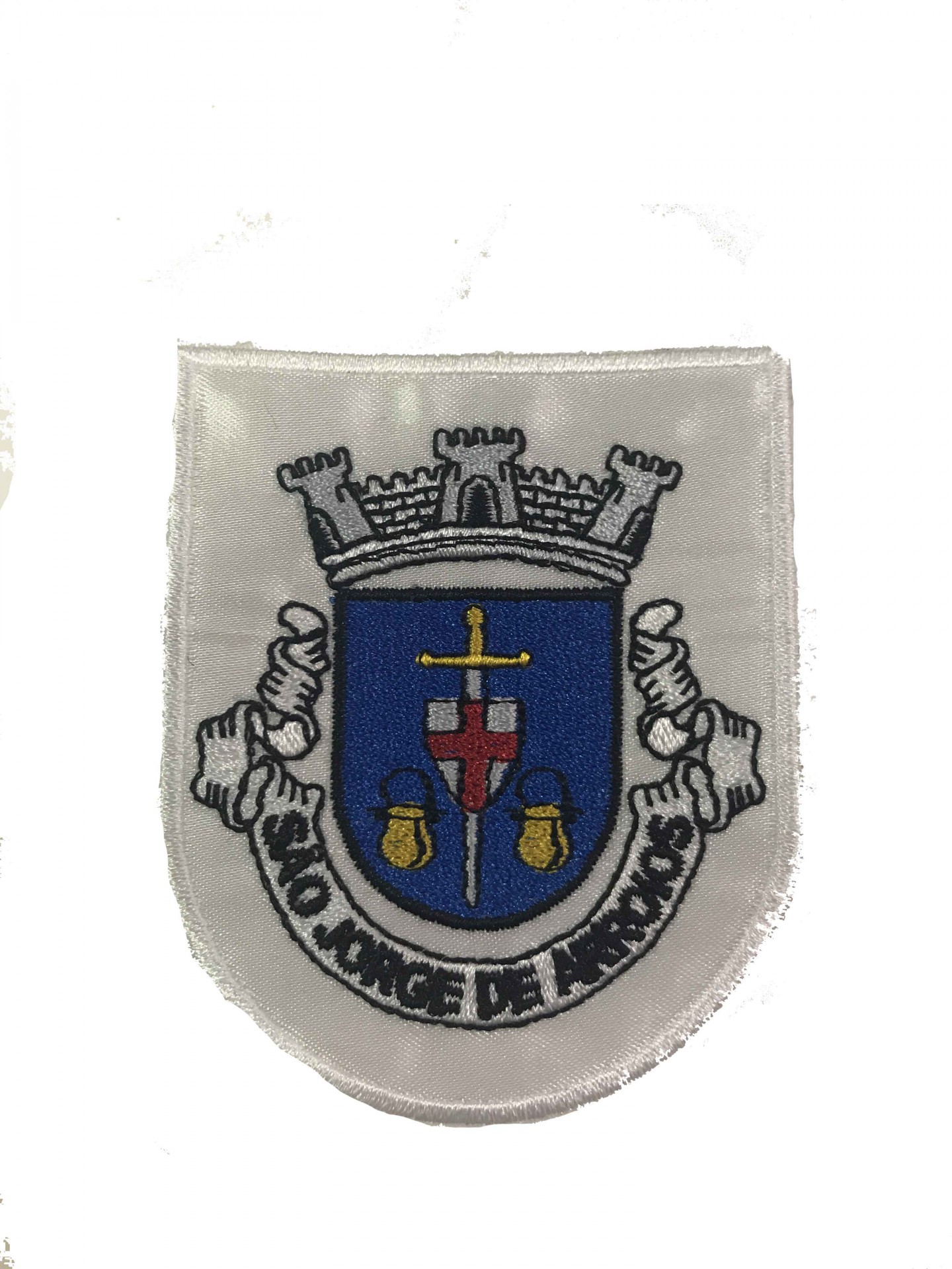 Emblema bordado branco com desenho de castelo, espada e sinos, texto 'SANTO ANTONIO DE MACAO'