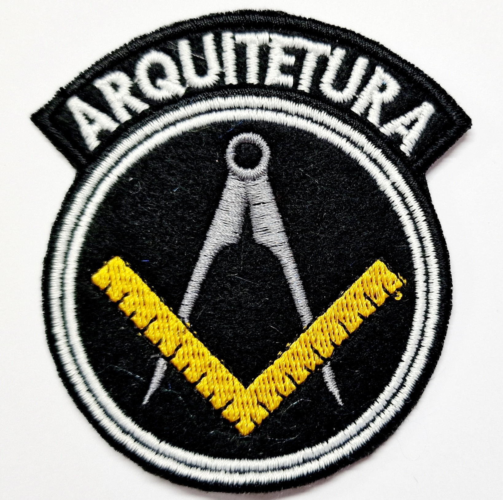 Emblema bordado preto com compasso, régua amarela e texto 'ARQUITETURA'