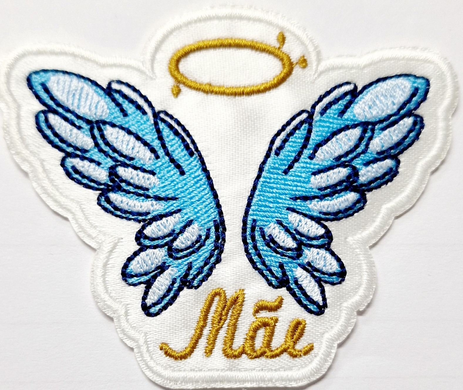 Patch bordado com asas azuis, aureola dourada e texto 'Mãe'