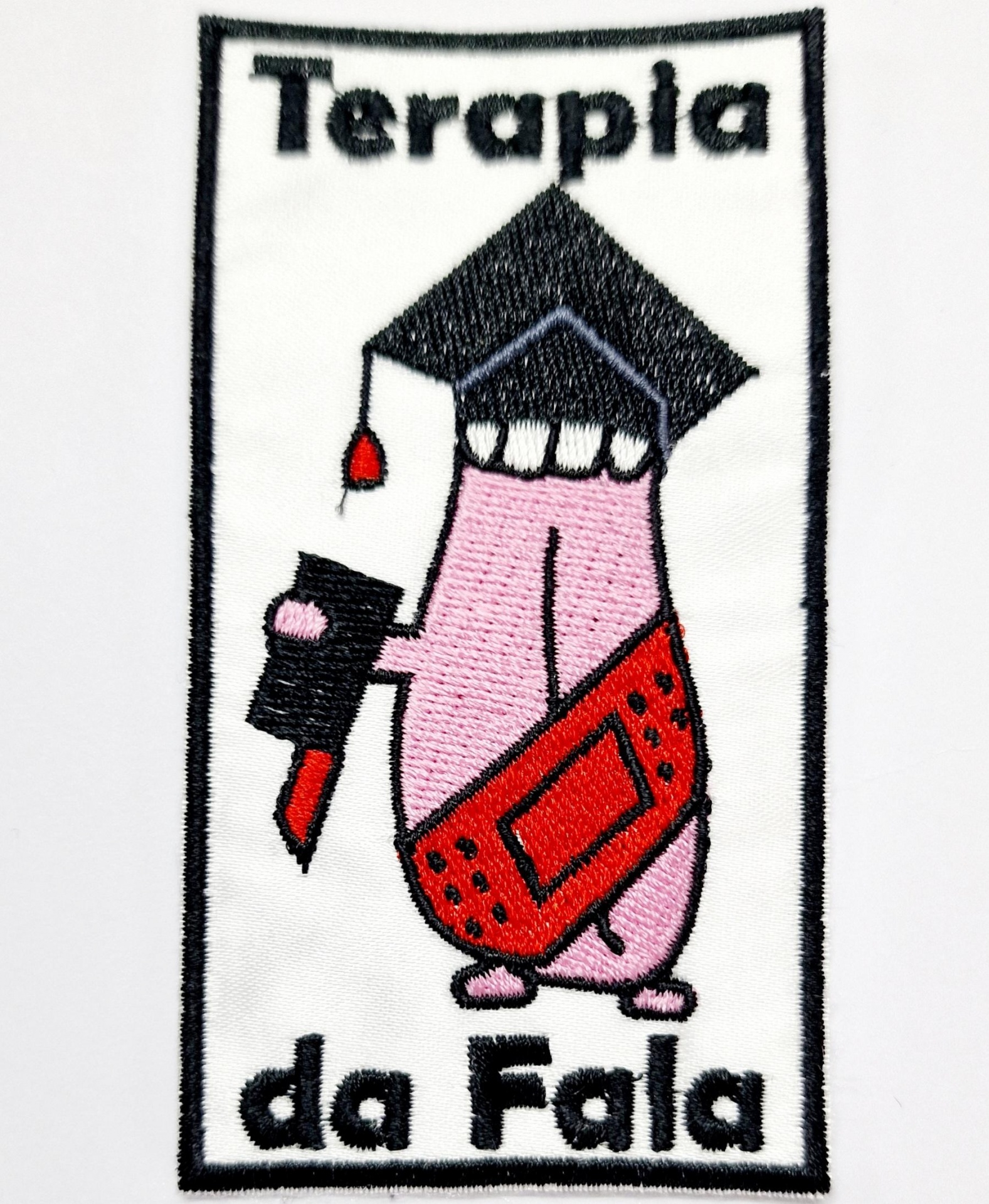 Bordado com texto Terapia da Fala e figura de língua com chapéu, microfone e aparelho auditivo