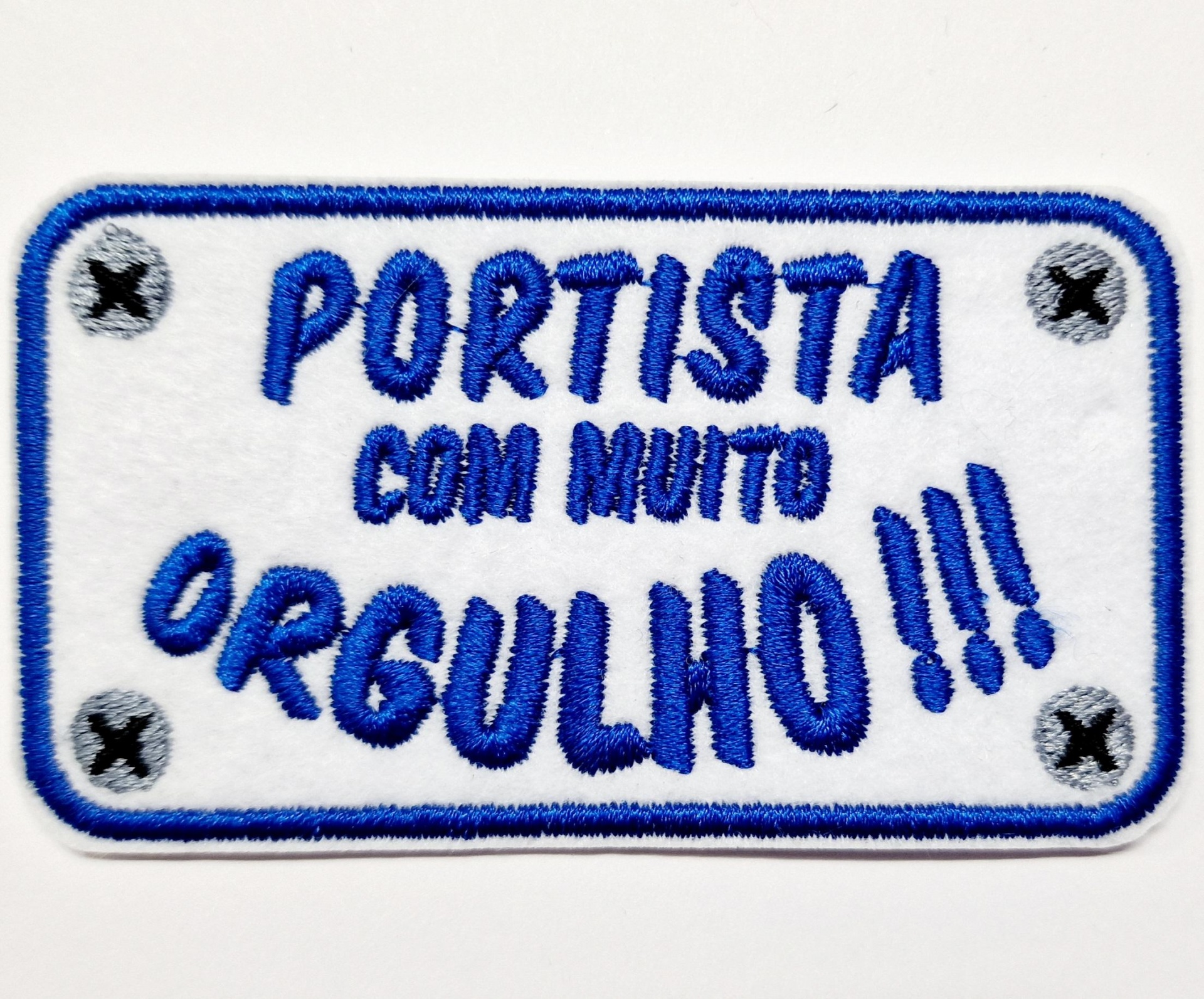 Patch bordado branco retangular com texto azul e cantos com pontos cinzentos e X pretos