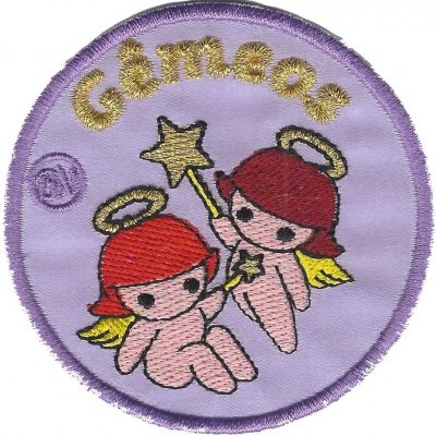Emblema bordado circular lilás com duas figuras de gémeos ruivos e palavra GEMEOS